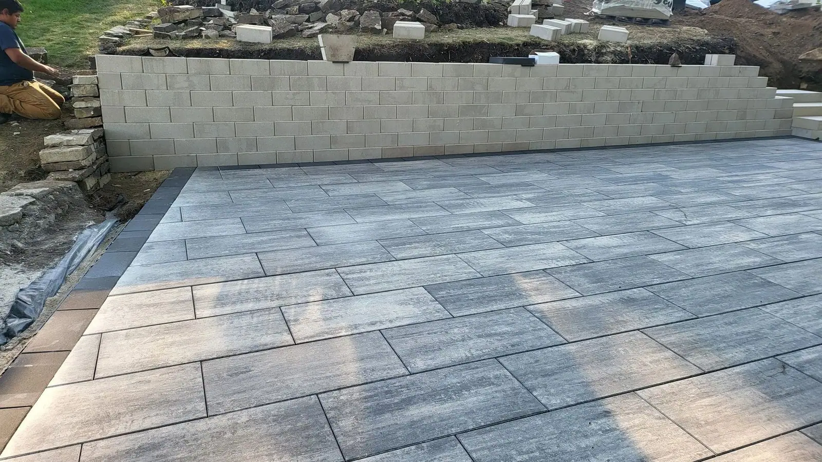 Patio de piedra natural frente a un muro de contención con jardinera elevada
