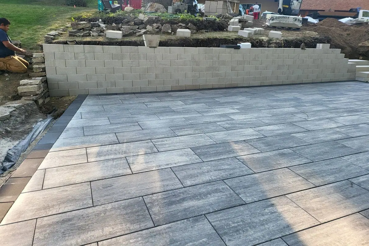Natural stone patio in front of a raised retaining wall and garden bed