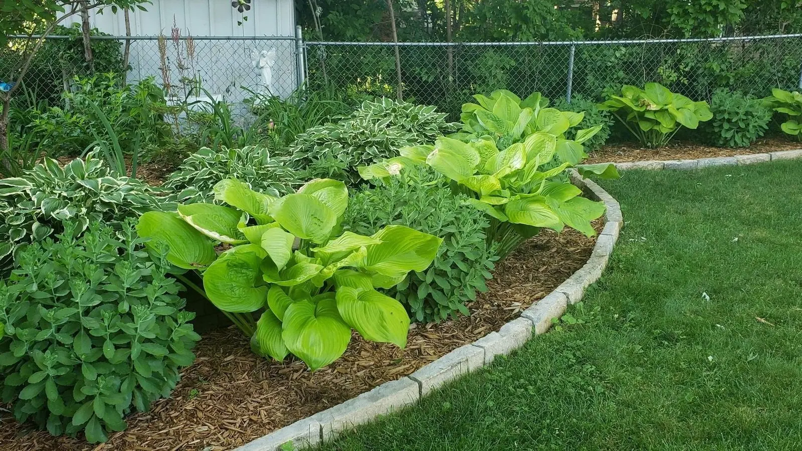 Jardinera curva con borde de piedra junto al césped